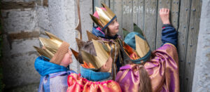 Sternsinger schreiben Segen an eine Kirchentür